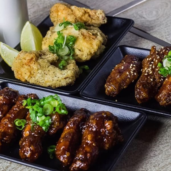 Three plates of chicken wings, two glazed with sauce and one crispy fried with lime.