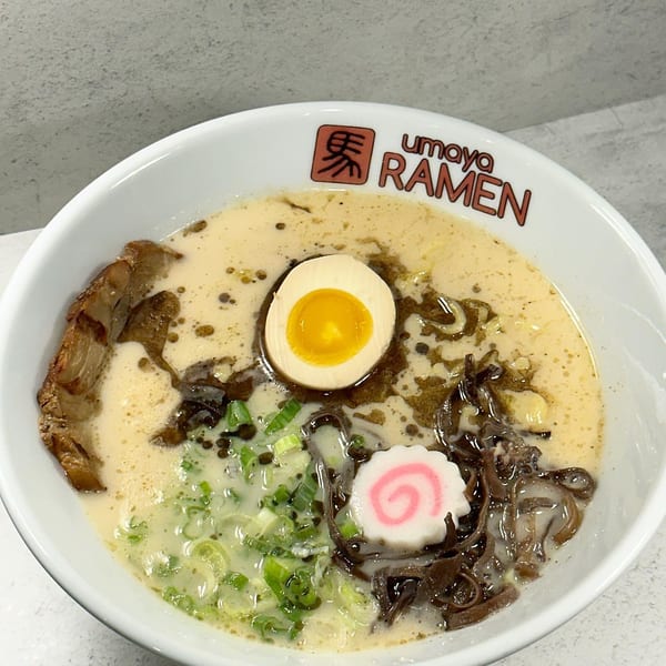 A bowl of Umoya Ramen with pork, egg, green onions, and a pink swirl fish cake.